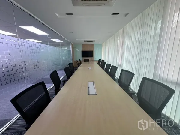 Office Space for rent - Large boardroom featuring an extended conference table, mesh chairs and wall-mounted display.