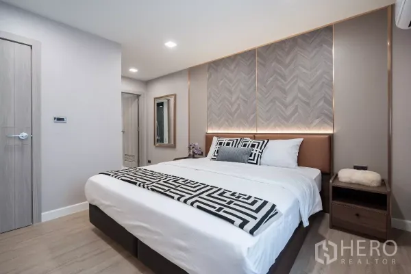 Apartment for rent - Master bedroom featuring a king bed, patterned headboard with ambient lighting and bedside tables.