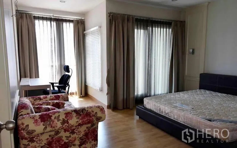 联排别墅 出租或出售在Wang Thonglang, Bangkok - 宽敞卧室，落地推拉门、书桌与扶手椅。