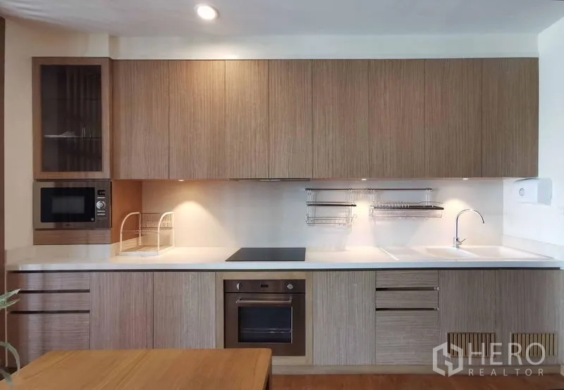 公寓 出租在Sathon, Bangkok - 一字型厨房，内置烤箱、灶台、微波炉与充足柜体。