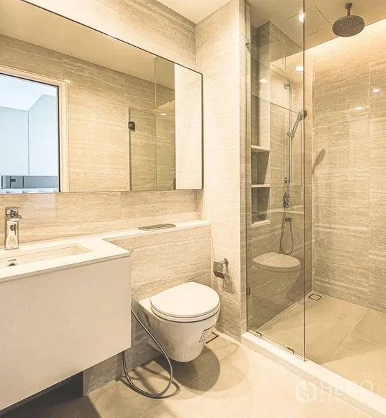 Condominium for rent in Bang Rak, Bangkok - Contemporary bathroom with wide mirror, floating vanity and glass-enclosed rain shower.