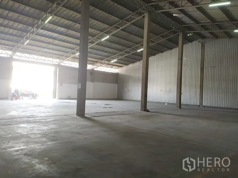 Warehouse for rent in Samut Prakan - Interior view showing wide truck-friendly entrance, concrete columns and bright natural light.