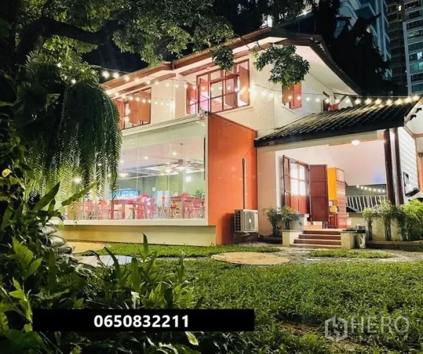 零售空间 出租在Pathum Wan, Bangkok - 夜间两层玻璃店屋，草坪与串灯点缀。