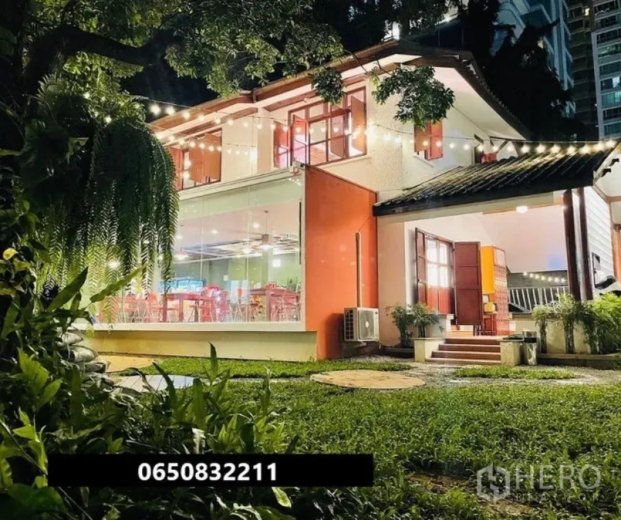 零售空间 出租在Pathum Wan, Bangkok - 夜间两层玻璃店屋，草坪与串灯点缀。