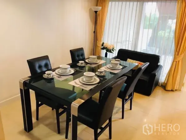 Townhouse for rent in Khlong Toei, Bangkok - Bright dining area with a glass table set for six beside full-height curtains and patio doors.
