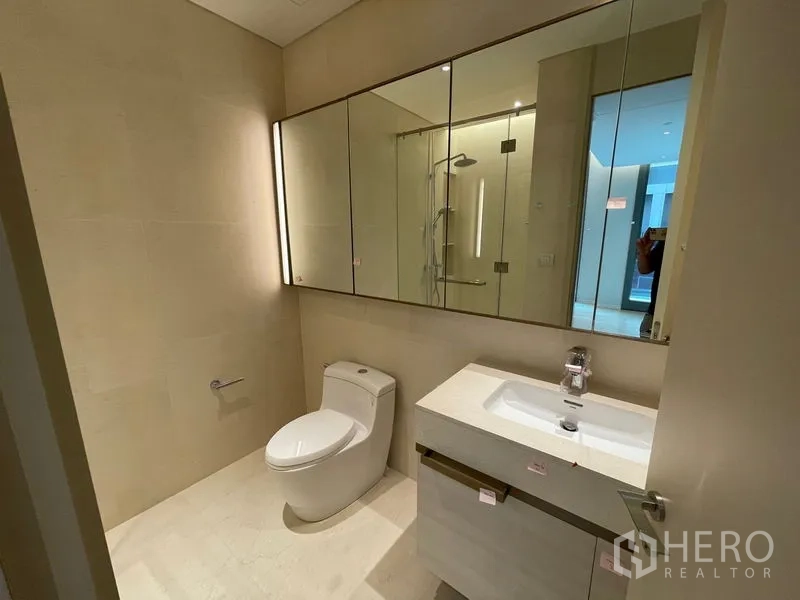 Condominium for rent or sale in Pathum Wan, Bangkok - Modern bathroom with mirrored cabinets, vanity and walk-in shower.