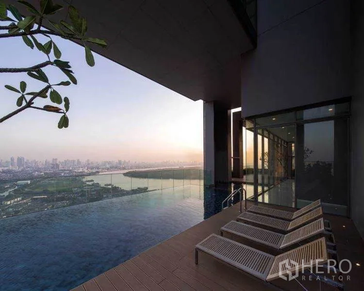 Condominium for rent or sale in Bang Rak, Bangkok - Infinity-edge sky pool with sun loungers and sweeping river and city views at sunset.