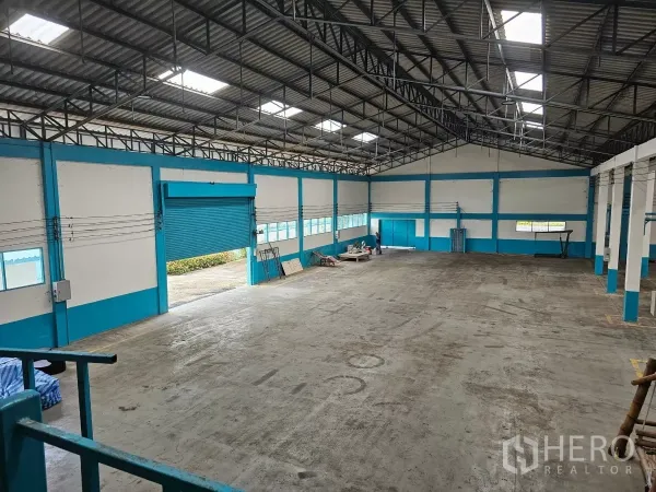 工厂 出租或出售在Mueang Rayong, Rayong - 工厂内部空间宽敞，钢梁高屋顶配采光板，重载混凝土地面与大型蓝色卷闸门。
