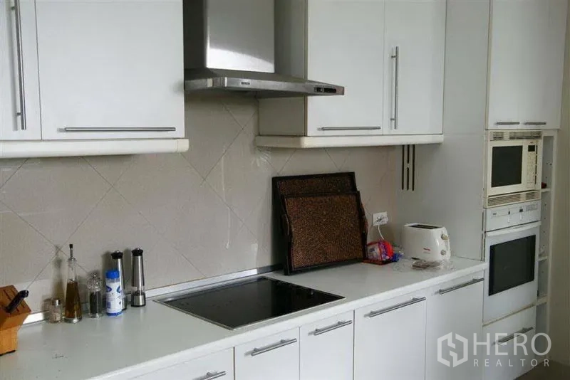 Detached House for rent in Phaya Thai, Bangkok - Modern white kitchen with built-in hob, hood, ovens and ample cabinetry.