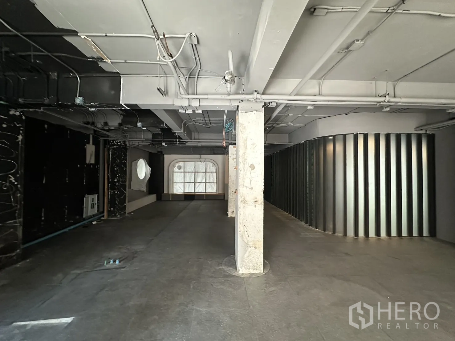 Retail Space for rent in Watthana, Bangkok - Spacious shell retail floor with central column, curved metal partition, and arched display window.