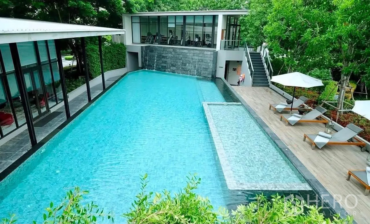 Townhouse for rent in Lat Phrao, Bangkok - Large swimming pool with sun deck, loungers and greenery by the clubhouse.