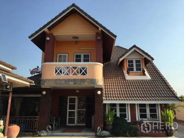 Detached House for rent or sale in Bang Bua Thong, Nonthaburi - Close-up of the front facade with balcony and dormer windows under a brown tiled roof.