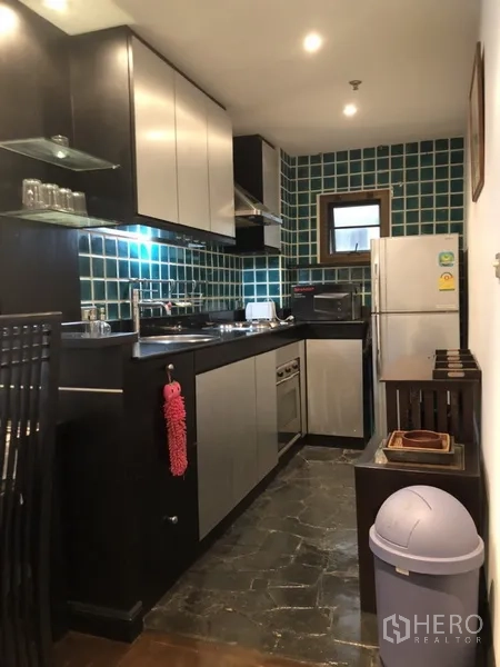 คอนโด ให้เช่าในWatthana, Bangkok - ครัวคอนโดพร้อมเคาน์เตอร์สีดำ ผนังกระเบื้องสีเขียว มีเตา เครื่องดูดควัน และตู้เย็น