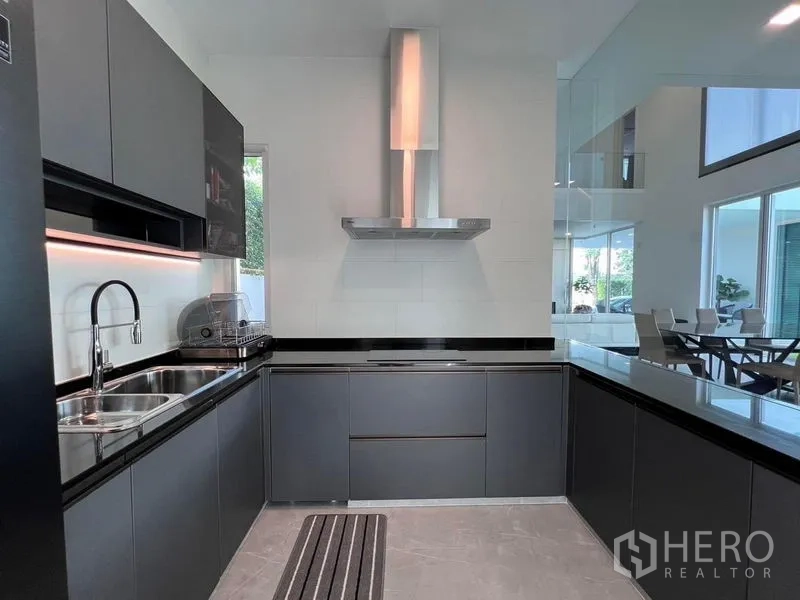 Detached House for sale in Samut Prakan - Second U-shaped kitchen with built-in hob, range hood, and black countertops.