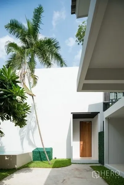 Office Space for rent in Watthana, Bangkok - Modern courtyard entry with white walls, shaded walkway and tropical landscaping.