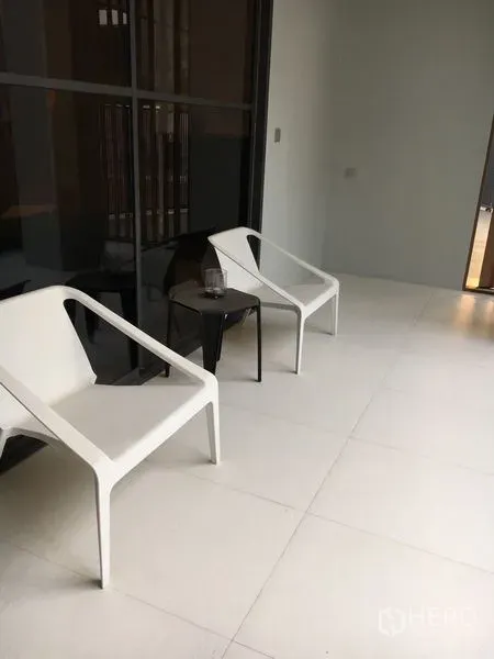 独立式住宅 出租在Wang Thonglang, Bangkok - 覆盖式露台，铺浅色地砖，摆放两把白色休闲椅和小边几。