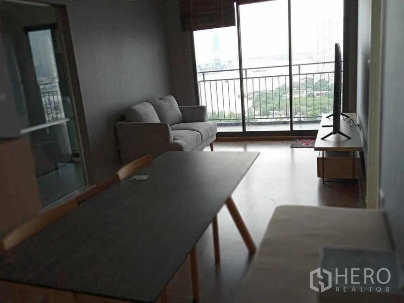 คอนโด ให้เช่าในYan Nawa, Bangkok - ห้องนั่งเล่นแบบโอเพ่น มีโซฟา โต๊ะทานข้าว และทีวี เปิดสู่ระเบียงวิวแม่น้ำ