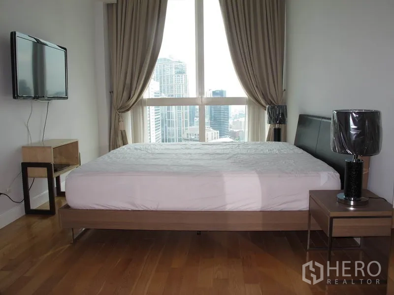 คอนโด ให้เช่าหรือขายในKhlong Toei, Bangkok - ห้องนอนใหญ่พร้อมหน้าต่างบานสูง วิวเมือง โต๊ะข้างเตียง และทีวีติดผนัง