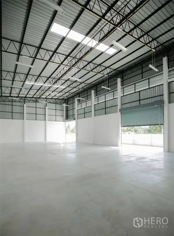 Factory for rent or sale in Nakhon Pathom - Warehouse interior with high ceiling, skylights, steel trusses and polished concrete floor.