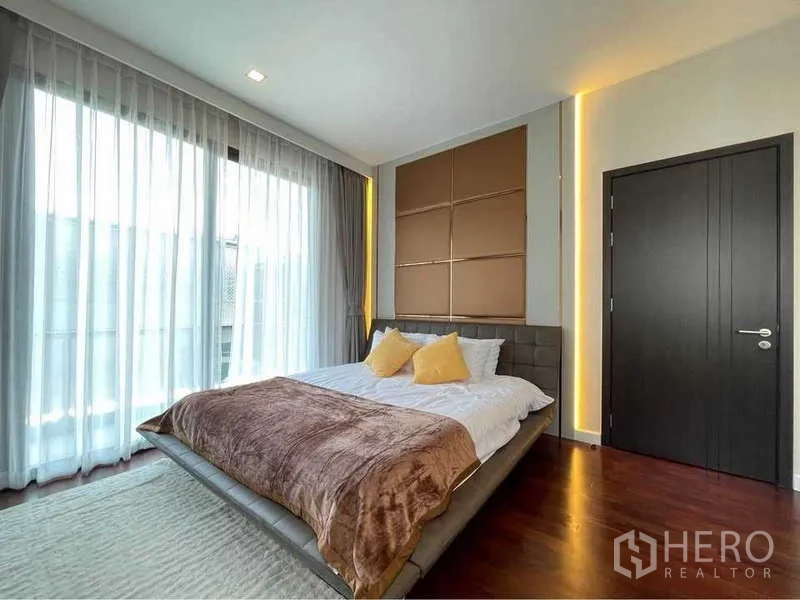 Detached House for rent in Bang Sue, Bangkok - Sunny bedroom with floor-to-ceiling curtains and feature wall panels.