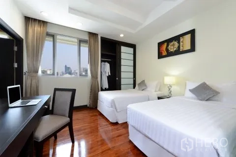 Apartment for rent in Watthana, Bangkok - Twin bedroom with city views, built-in wardrobe, and work desk by the window.