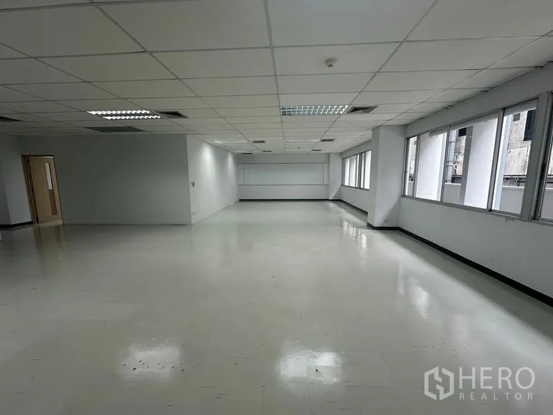 Office Space for rent in Bang Rak, Bangkok - Spacious office floor with corner windows, fluorescent lighting, and neutral walls ready for fit-out.