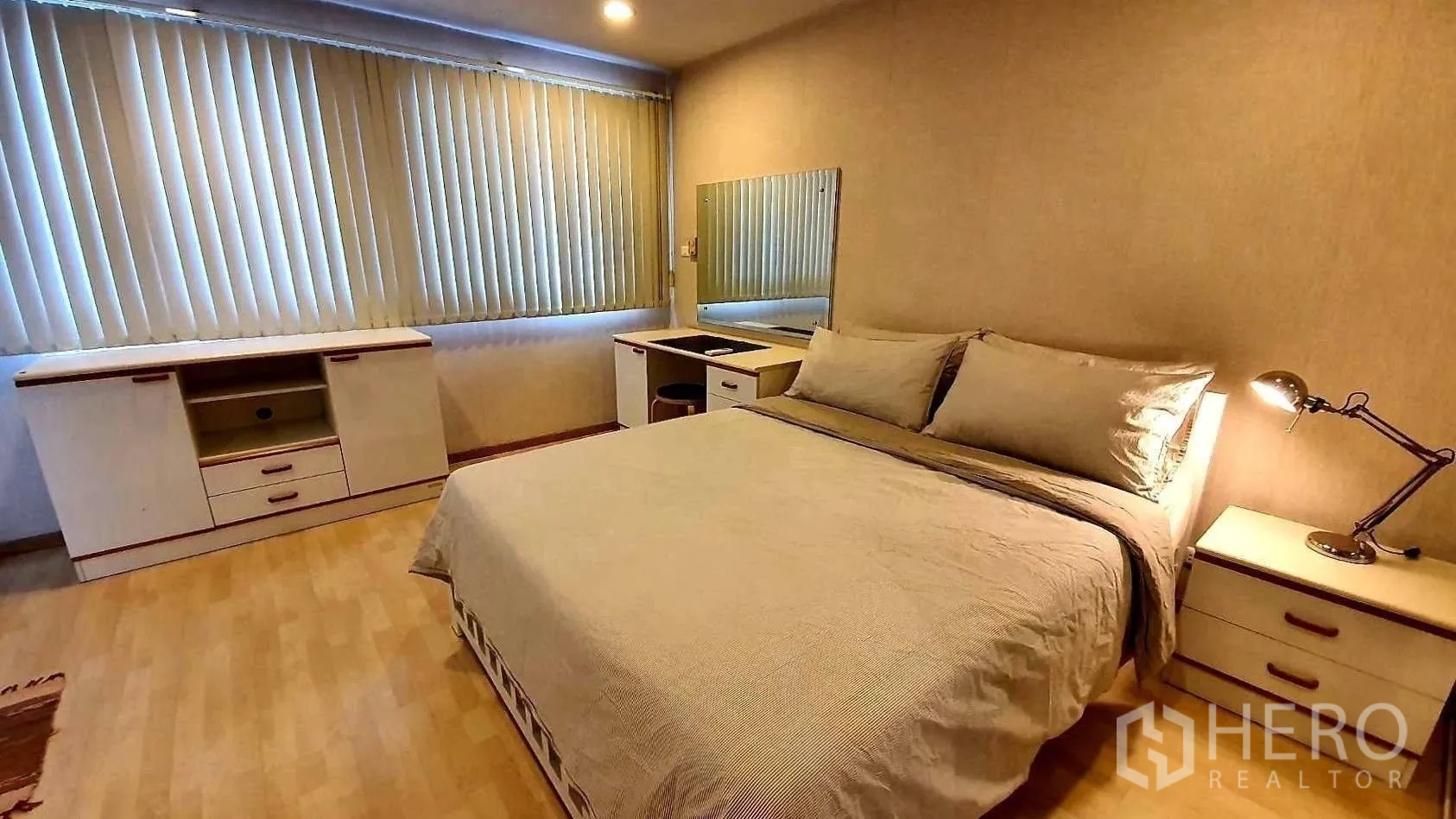 Condominium for rent in Khlong Toei, Bangkok - Bedroom with large windows and vertical blinds, bed, desk and sideboard.