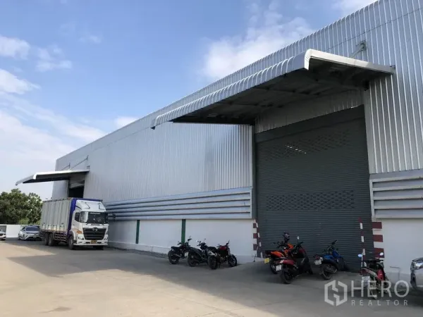 Warehouse for rent in Pathum Thani - Side view of the warehouse façade showing a covered dock, high-clear roof and spacious driveway for trailers.