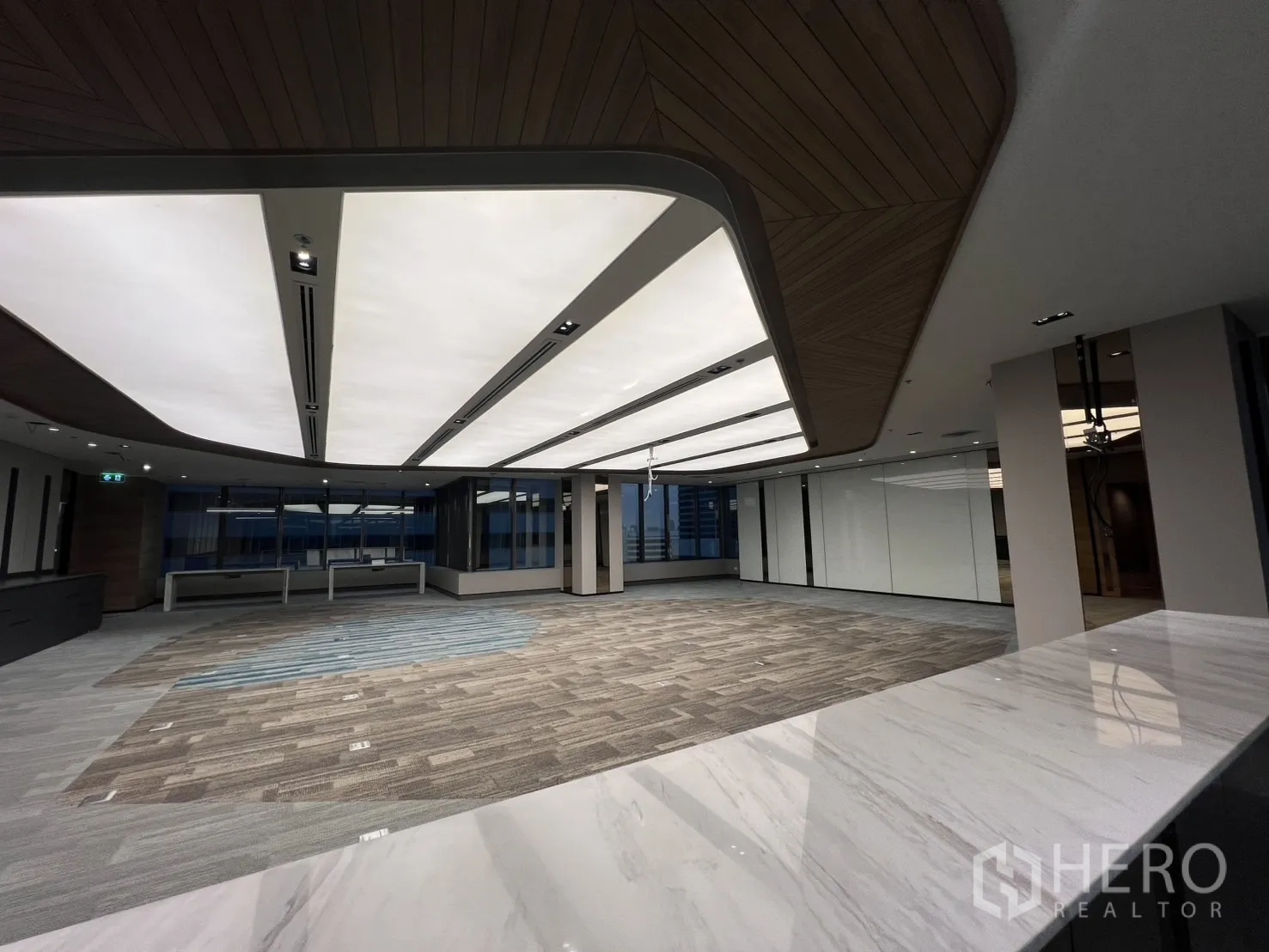 办公空间 出租在Huai Khwang, Bangkok - 从大理石台面望向开放办公层，玻璃隔间与现代照明。