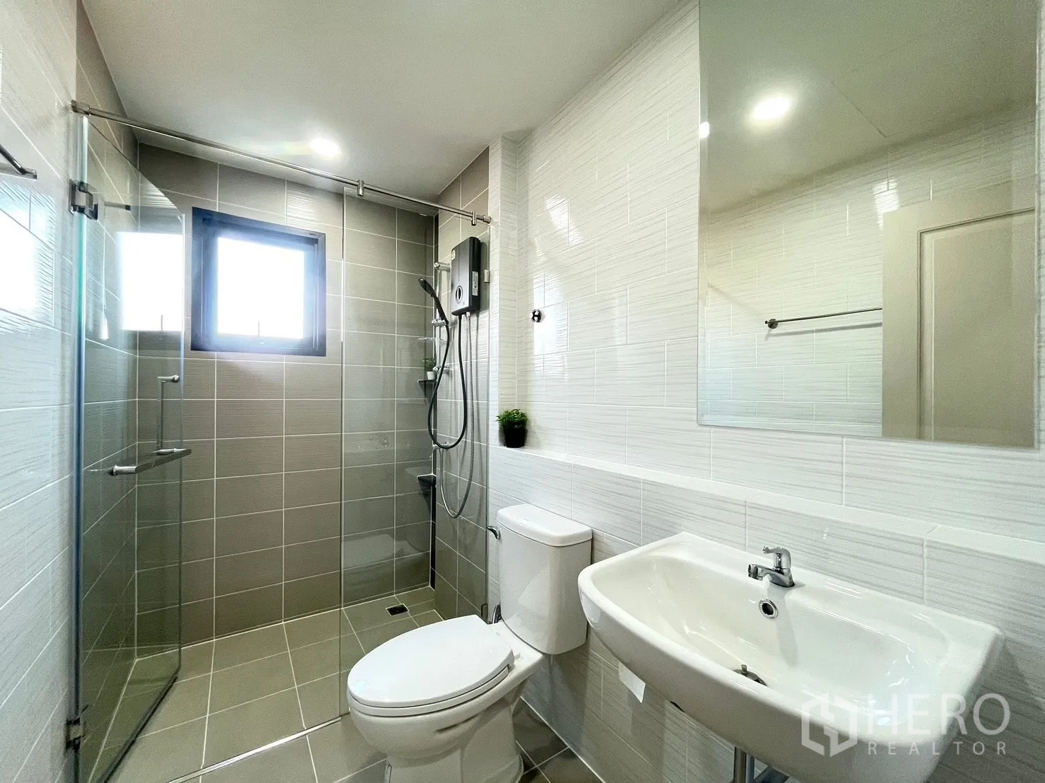 Detached House for rent in Bang Phli, Samut Prakan - Clean bathroom with a glass-enclosed shower, white sink and toilet, tiled walls and a window.