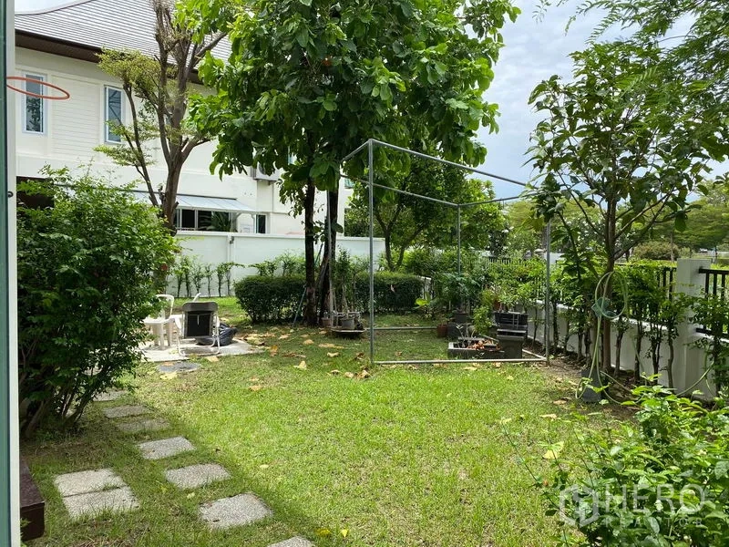 Detached House for rent in Prawet, Bangkok - Private corner garden with lawn, mature trees and white perimeter fence.