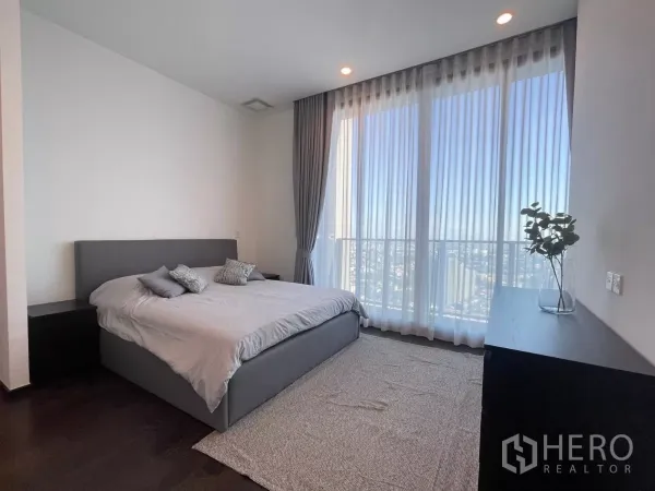 Condominium for rent in Phra Khanong, Bangkok - Sunlit master bedroom with king bed, full-height curtains and sweeping city views.