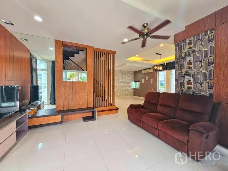 บ้าน ให้เช่าในChatuchak, Bangkok - ห้องนั่งเล่นแบบโอเพนพลาน โซฟาขนาดใหญ่ พัดลมเพดาน และฉากกั้นไม้