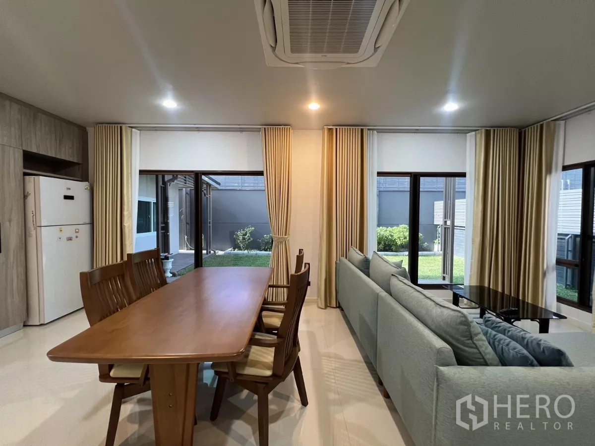 Detached House for rent or sale in Bang Kapi, Bangkok - Wood dining table beside sliding glass doors opening to the garden