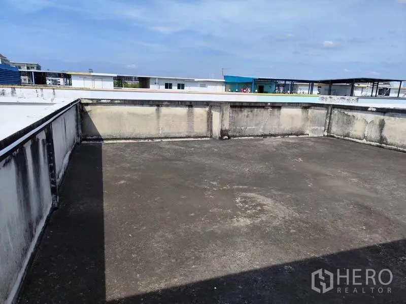 Shophouse for sale in Pathum Thani - Open concrete rooftop terrace with low parapet walls and city views.