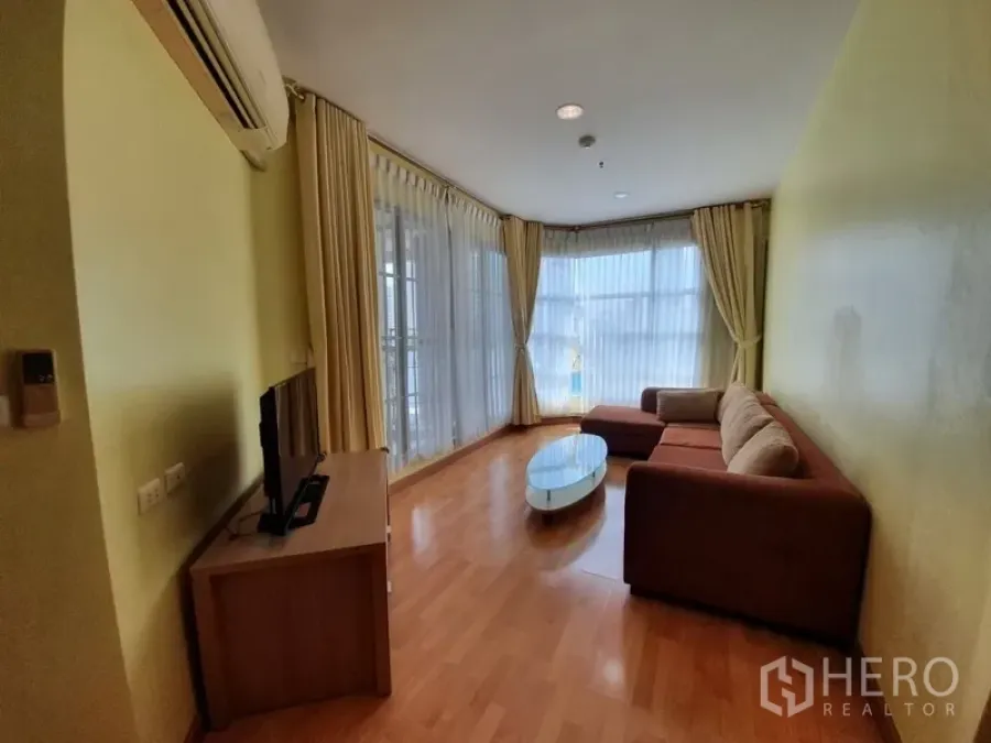 คอนโด ให้เช่าในKhlong Toei, Bangkok - ห้องนั่งเล่นมุมกว้าง พื้นไม้ หน้าต่างกระจกเต็มบาน ผ้าม่าน และโซฟา L-shape