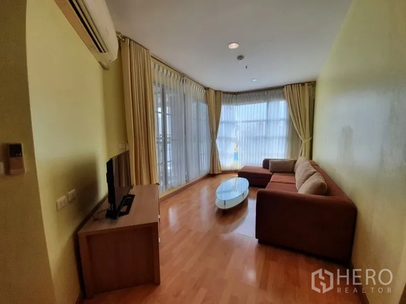 คอนโด ให้เช่าในKhlong Toei, Bangkok - ห้องนั่งเล่นมุมกว้าง พื้นไม้ หน้าต่างกระจกเต็มบาน ผ้าม่าน และโซฟา L-shape