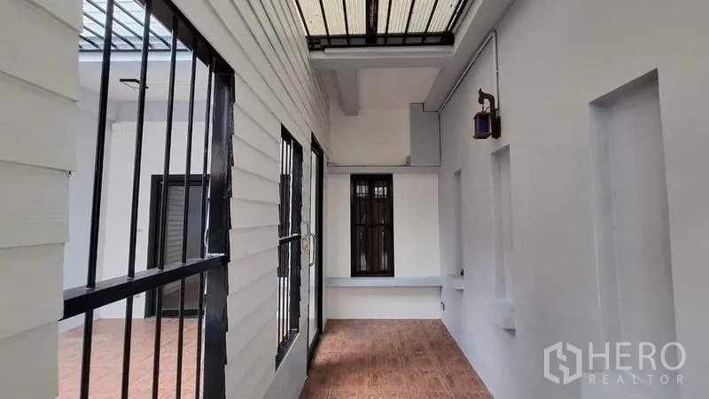 ทาวน์เฮาส์ ให้เช่าหรือขายในChatuchak, Bangkok - โถงระเบียงด้านข้างแบบมีหลังคา ผนังสีขาวและเหล็กดัดสีดำ