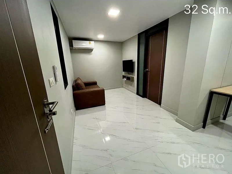 零售空间 出售在Khlong Toei, Bangkok - 现代室内，亮面地砖，壁挂电视、空调与棕色沙发。