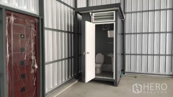 Warehouse for rent in Bang Lamung, Chon Buri - Built-in warehouse restroom with toilet and sink inside metal-panel structure.