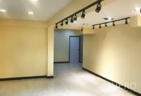 办公空间 出租在Bang Rak, Bangkok - 明亮办公室内景，天花轨道灯、素色墙面与通往独立空间的门。