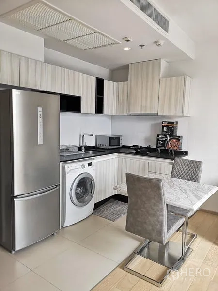 公寓 出租在Watthana, Bangkok - 现代厨房配大冰箱、洗衣机、灶台与充足柜体。