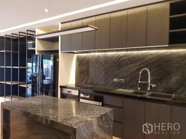 Condominium for rent in Bang Rak, Bangkok - Modern open kitchen with dark stone island, full-height cabinets and soft LED lighting.