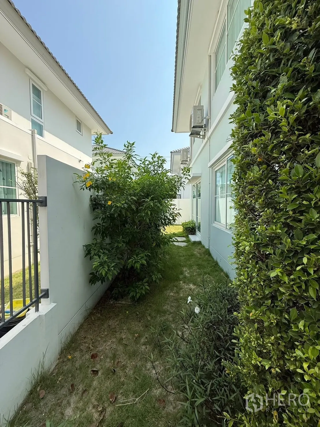 独栋房屋 for rent in Bang Phli, Samut Prakan - 房屋侧院的狭长草地，两侧为绿篱与墙体。