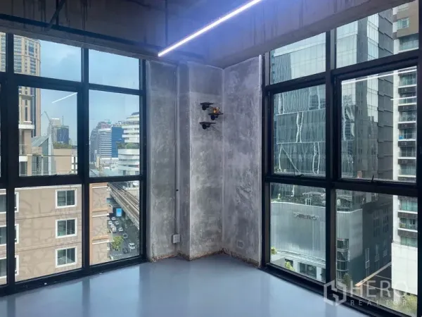 สำนักงาน ให้เช่าในKhlong Toei, Bangkok - มุมสำนักงานผนังคอนกรีตเปลือยและกระจกกริดบานใหญ่ เห็นวิวเมือง พร้อมไฟเส้น LED.