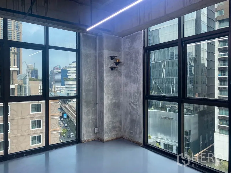 สำนักงาน ให้เช่าในKhlong Toei, Bangkok - มุมสำนักงานผนังคอนกรีตเปลือยและกระจกกริดบานใหญ่ เห็นวิวเมือง พร้อมไฟเส้น LED.