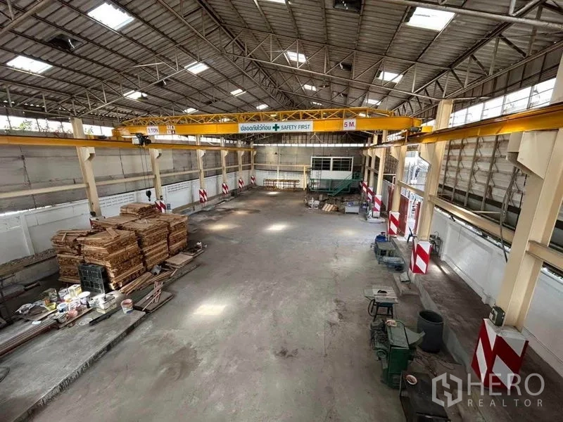 คลังสินค้า ให้เช่าในMueang Samut Prakan, Samut Prakan - ภาพมุมกว้างของโกดัง แสดงเครนเหนือศีรษะและกองไม้แปรรูป