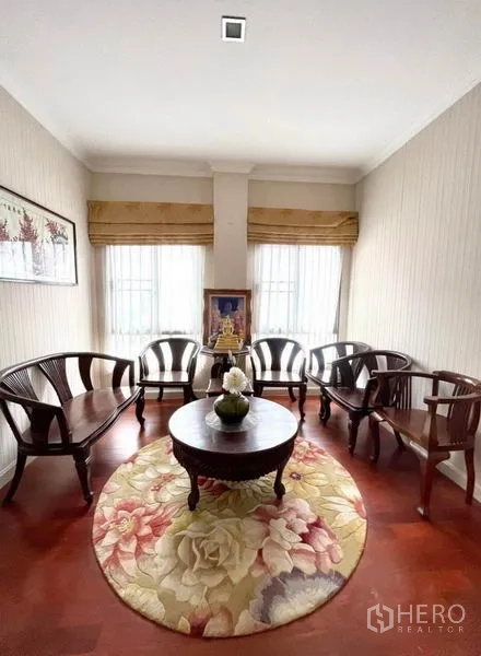 独立式住宅 出租在Prawet, Bangkok - 二层会客角，圆地毯与木椅，光线明亮。