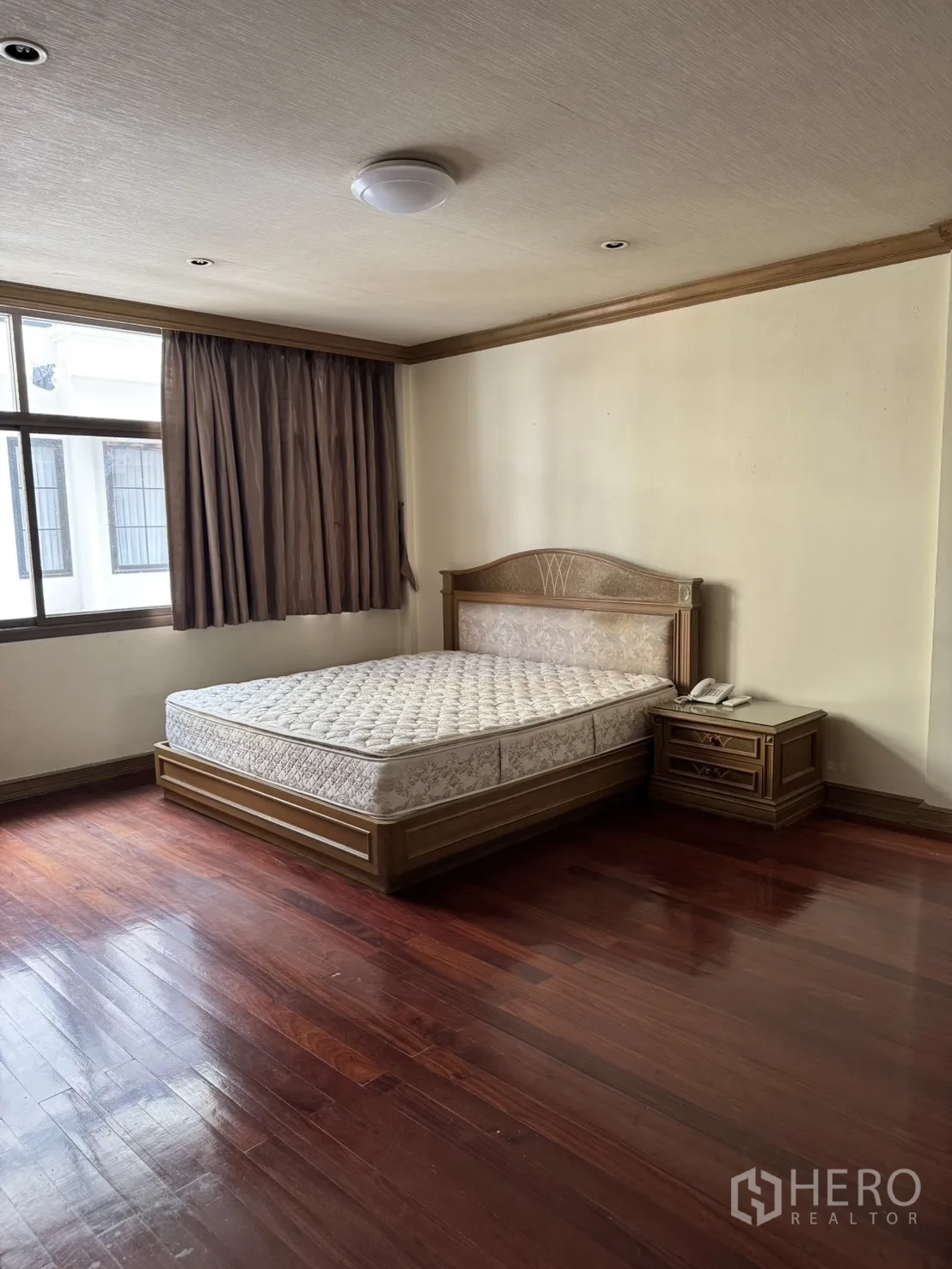 Home Office for rent in Watthana, Bangkok - Bright bedroom with large window, bed, and hardwood flooring.