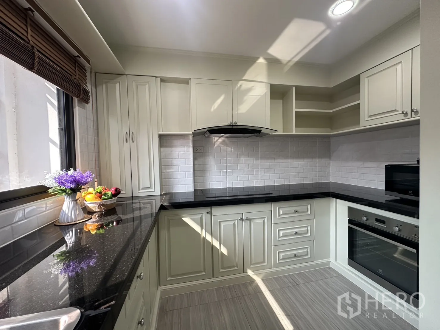 Condominium for rent in Watthana, Bangkok - L-shaped kitchen with white cabinetry, black granite counters, and oven.